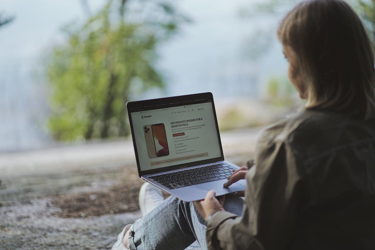 Woman using a laptop outdoors in Helsinki, Finland, showcasing a remote work lifestyle.